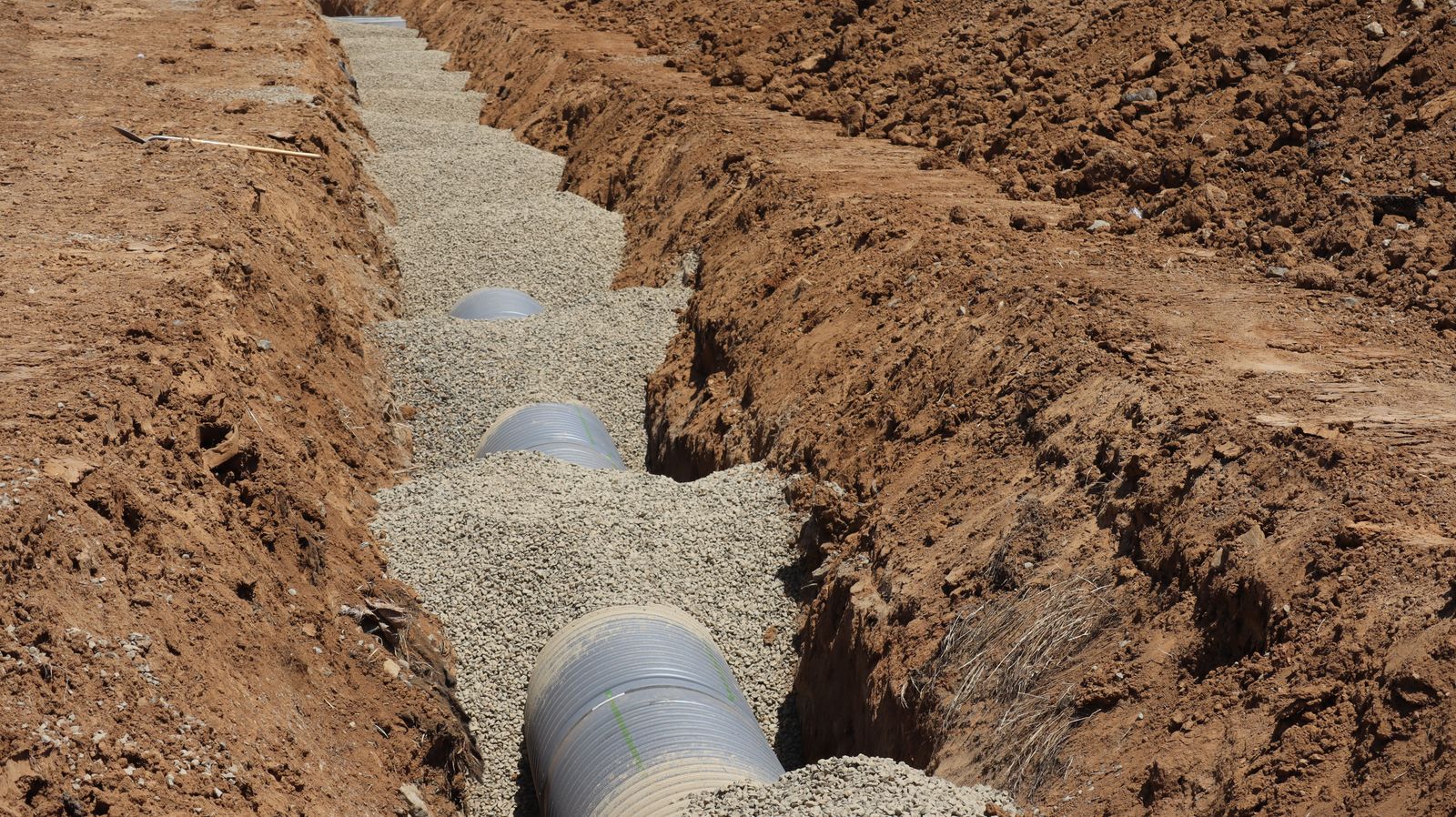 Residential sewer line replacement trench with new pipe installed in sandy coastal soil