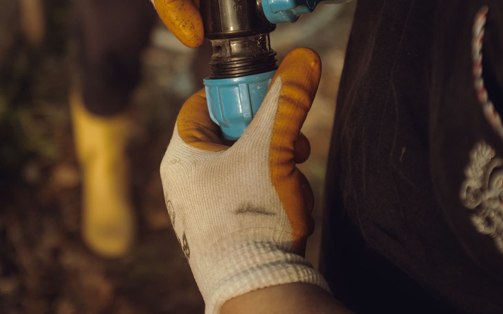Plumber joining a new sewer pipe section by hand at a small excavation access point during a trenchless repair